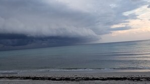Une plage avec une mer calme et un ciel nuageux.