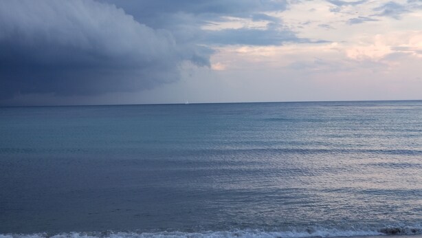 Ein Strand mit ruhigem Meer und bewölktem Himmel.