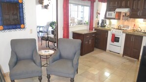 A kitchen with two armchairs, a dining table, and a window with curtains. - lovely suite getaway (Puerto Vallarta)