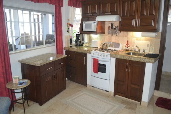 A kitchen with wooden cabinets, a gas stove, a microwave, and a sink.