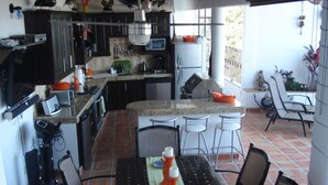 A kitchen with a dining area, including a table with chairs, a refrigerator, and various kitchen appliances. - lovely suite getaway (Puerto Vallarta)