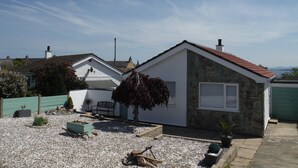 A modern house with a stone facade, a red roof, and a garden with gravel and plants. - Penmon View, Moelfre, Anglesey. With sea and mountain views. (Moelfre)