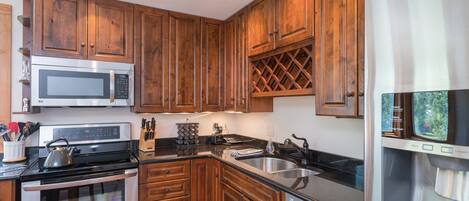 A modern kitchen with wooden cabinets, stainless steel appliances, and a built-in wine rack.