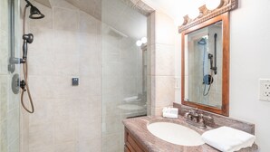 A bathroom with a glass-enclosed shower, a sink with a marble countertop, and a mirror with a wooden frame. - Beautifully Remodeled - Steps to Lift 7 and River Trail with Mountain Views (Telluride)