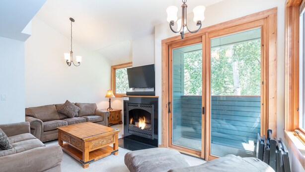 A cozy living room with a fireplace, a sofa, a coffee table, and a television. - Beautifully Remodeled - Steps to Lift 7 and River Trail with Mountain Views (Telluride)
