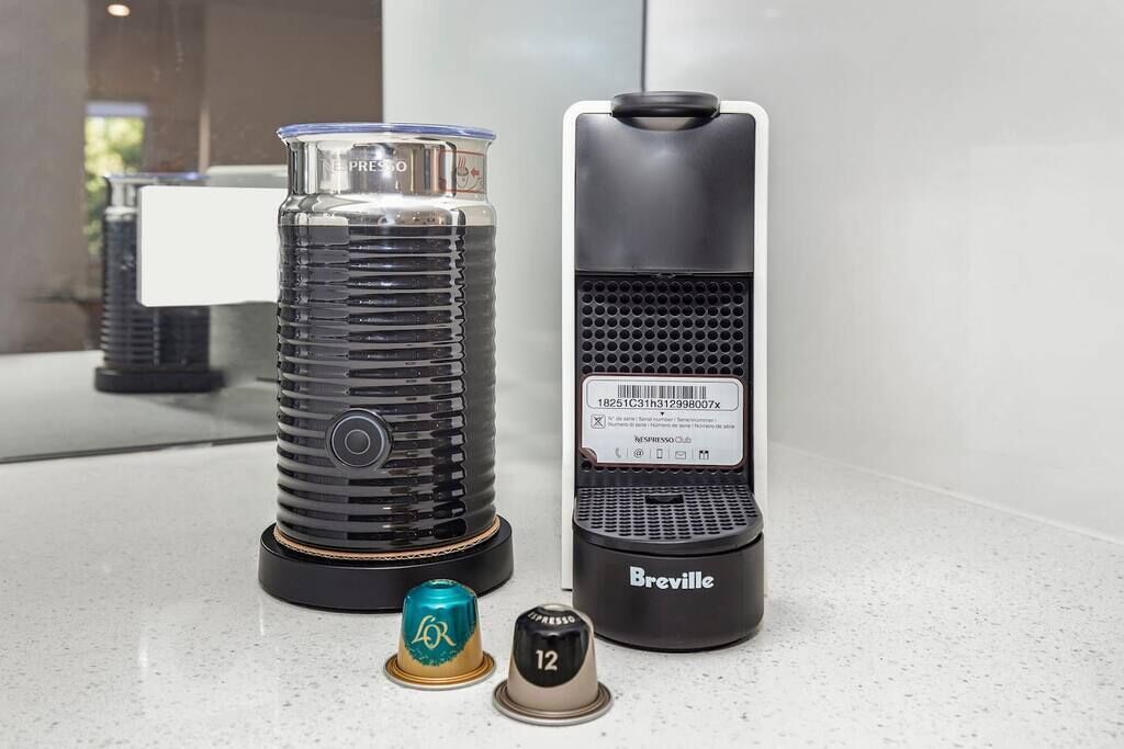 Deux machines à café, l’une portant l’inscription « Presso » et l’autre « Breville », avec des capsules de café devant.