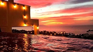 Een zonsondergang vanaf een hotel aan het water, met een steiger die het water in loopt.
