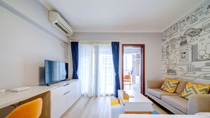 Quarto de hotel moderno com televisão de tela plana, escrivaninha, cama e sofá.
