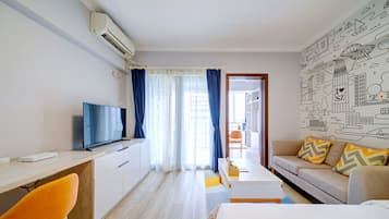 A modern hotel room with a flat-screen TV, a desk, a bed, and a sofa.