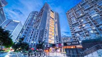 A high-rise building with multiple floors, a prominent entrance with signage, and a staircase leading to the entrance.
