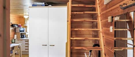 Ein Holzinnenraum mit einem weißen Kleiderschrank, einer Holztreppe und einem Küchenbereich mit einer Mikrowelle.