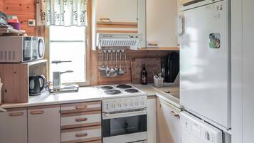 A compact kitchen with a stove, oven, microwave, and refrigerator.