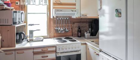 A compact kitchen with a stove, oven, microwave, and refrigerator.