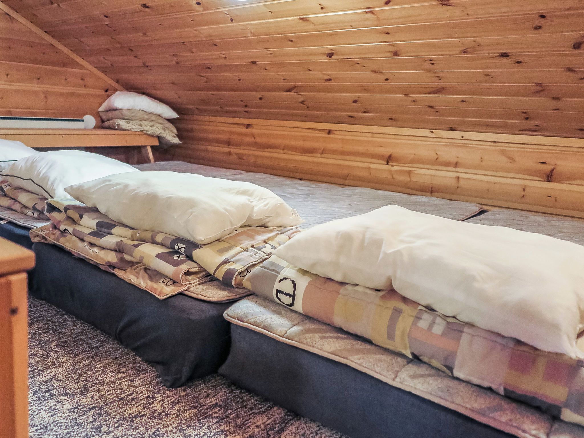 Un lit simple avec une couette et des oreillers dans une chambre de cabane en bois.
