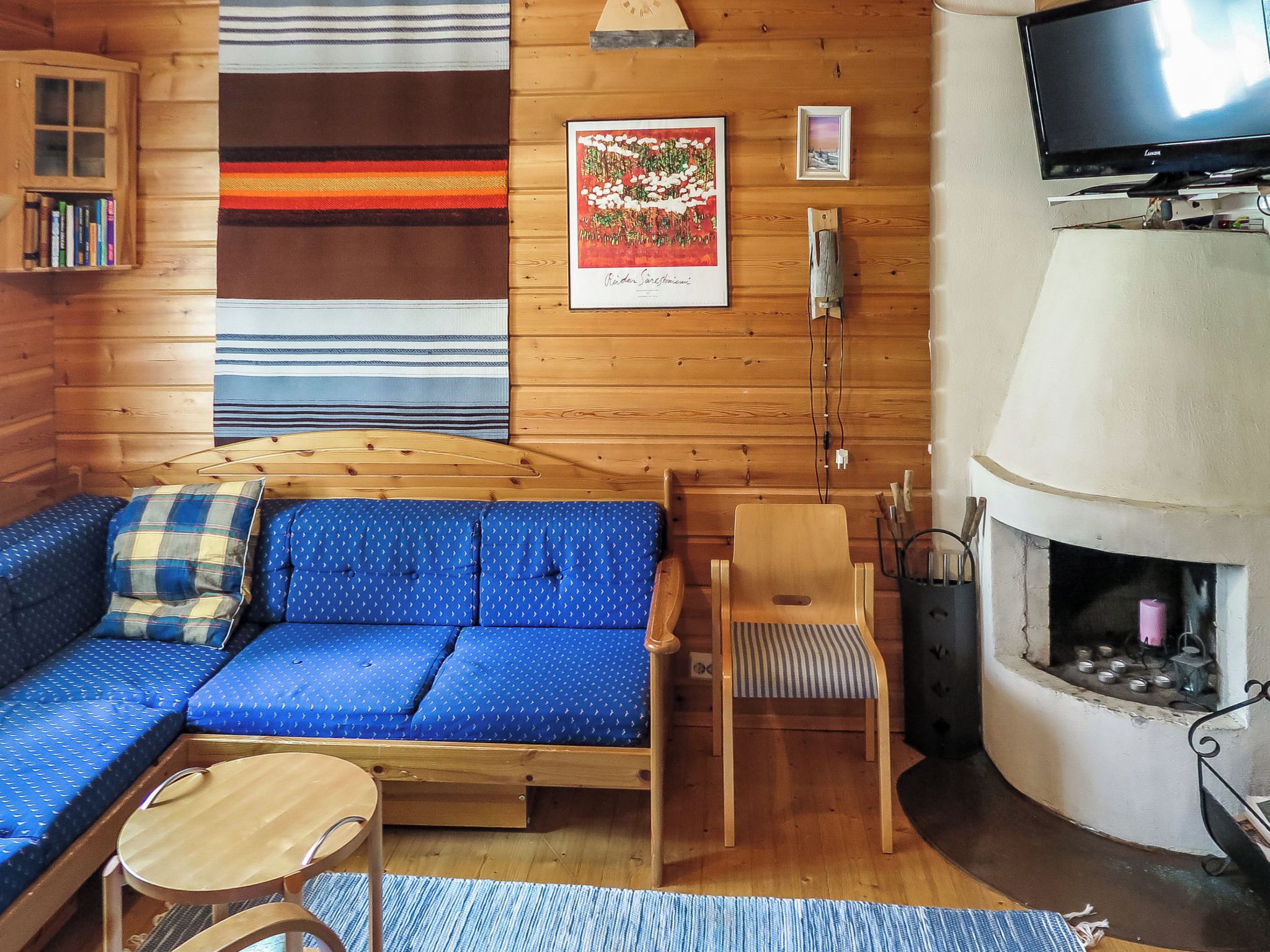 Een gezellig chaletinterieur met een houten bank, een kleine tafel, een stoel, een open haard en een televisie.