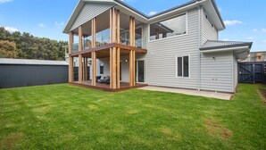 A modern two-story house with a covered patio and a fenced backyard.