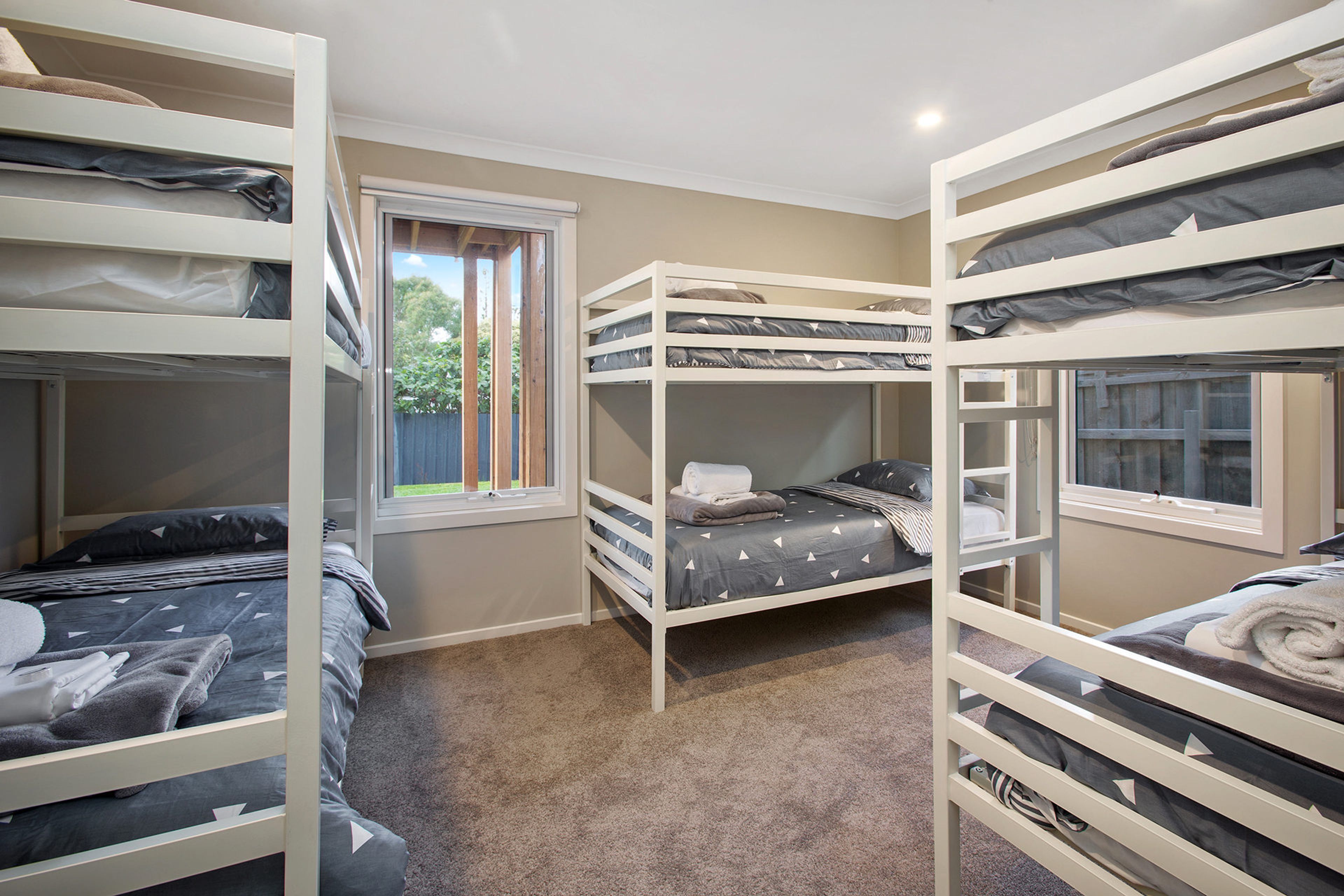 Een kamer met stapelbedden, een raam en een vloerbedekking.
