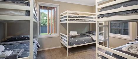 Een kamer met stapelbedden, een raam en een vloerbedekking.