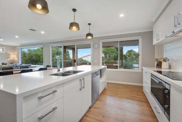 A modern kitchen with a large island, built-in appliances, and large windows offering views of the outdoors.