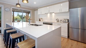 A modern kitchen with a large island, stainless steel appliances, and a view to the outdoors.