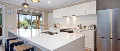 A modern kitchen with a large island, stainless steel appliances, and a view to the outdoors.