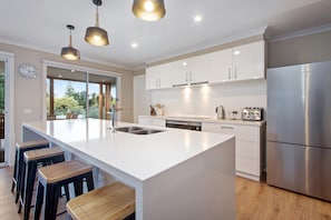 A modern kitchen with a large island, stainless steel appliances, and a view to the outdoors.