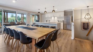 A modern kitchen with a central island, dining area with chairs, and a view of the outdoors.