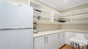 A modern kitchen with white cabinetry, a built-in blender, and a white high chair.