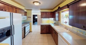 Kitchen features a central island with a sink and stove, wooden cabinets, and a window.