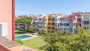 Un hôtel à plusieurs étages doté de balcons, d’une piscine et d’un jardin bien entretenu.
