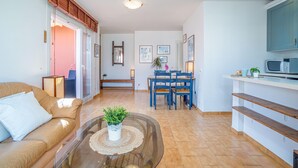 Un salon moderne avec une table basse en verre, un canapé en cuir et un coin repas comprenant une table et des chaises bleues.
