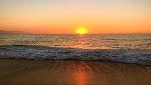 Une plage au coucher du soleil, avec des vagues qui se rapprochent du rivage.