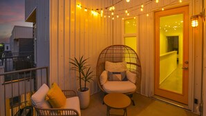 A balcony with wicker chairs, a small table, and string lights.