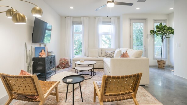 A modern living room with a sofa, two armchairs, a coffee table, and a flat-screen TV mounted on the wall.