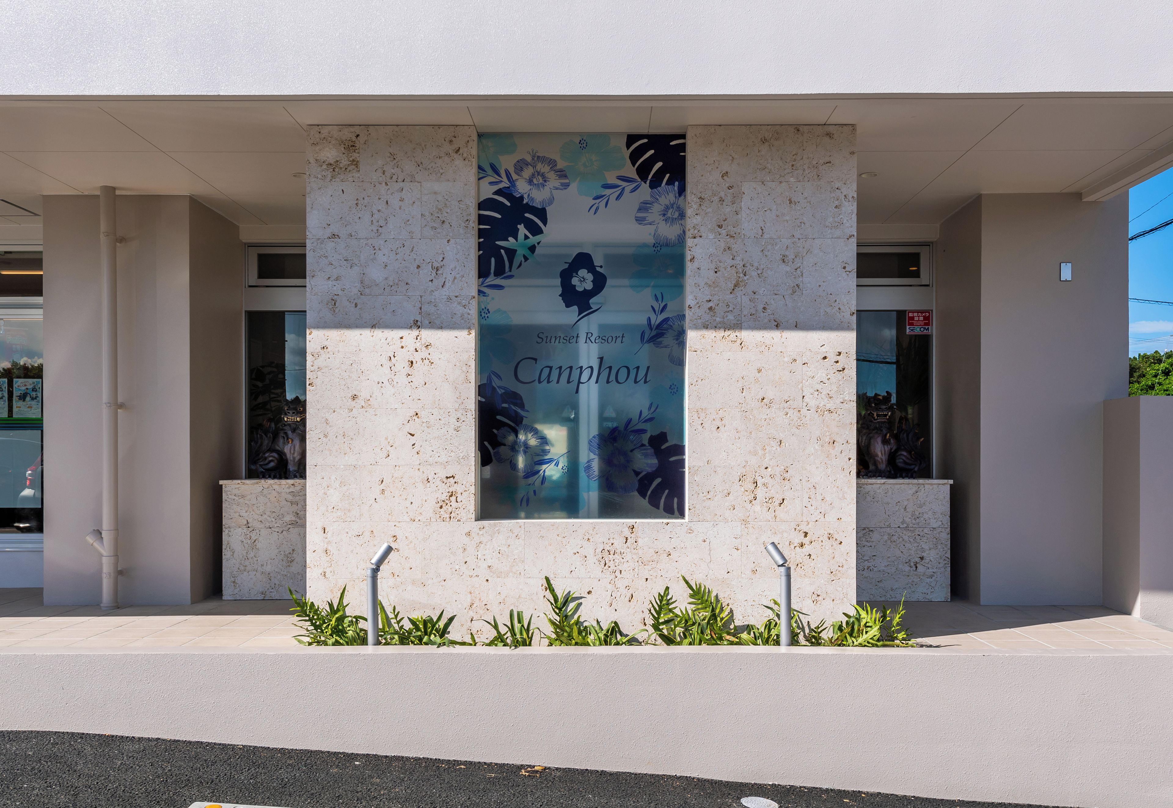 A building facade with a large vertical banner displaying 'Sunset Resort Canphou' and a floral design.