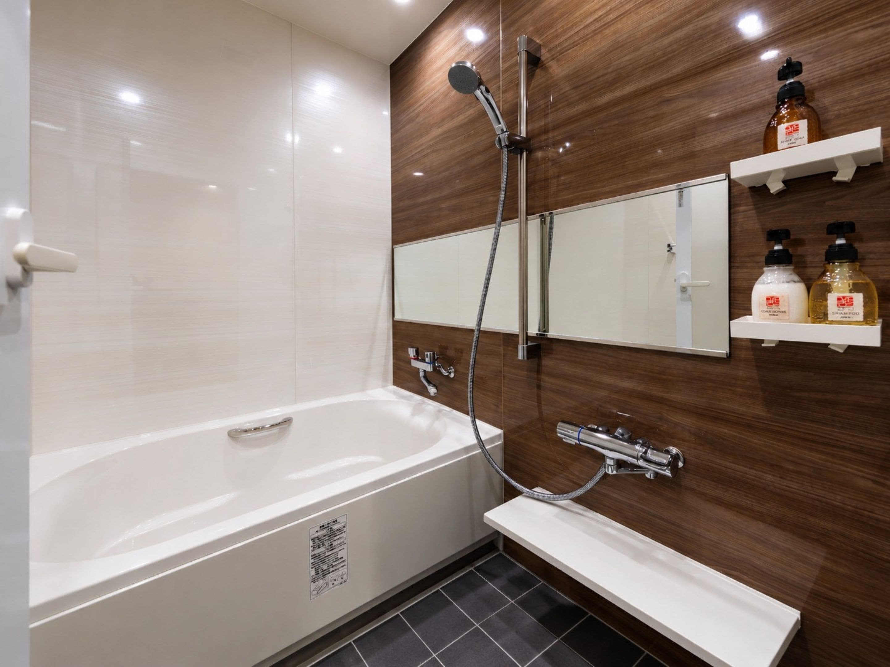 A modern bathroom with a bathtub, a shower, a sink, and a mirror. There are two shelves with toiletries.