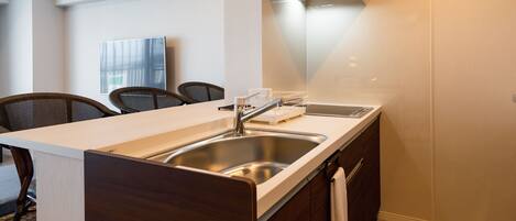 Una cocina moderna con un lavaplatos integrado, estufa y microondas. Hay un comedor con sillas y una mesa.