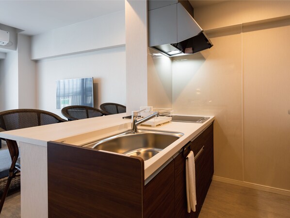 Una cocina moderna con un lavaplatos integrado, estufa y microondas. Hay un comedor con sillas y una mesa.
