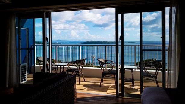 A balcony with a view of the sea, a table, and two chairs. - Sunset Resort Canphou (Motobu)