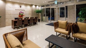 A reception area with a reception desk, chairs, sofas, and a potted plant. - Sunset Resort Canphou (Motobu)