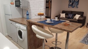 A compact kitchen with a washing machine, a microwave, and a small island with bar stools. - San Lorenzo beach front center apartment (Gijón)
