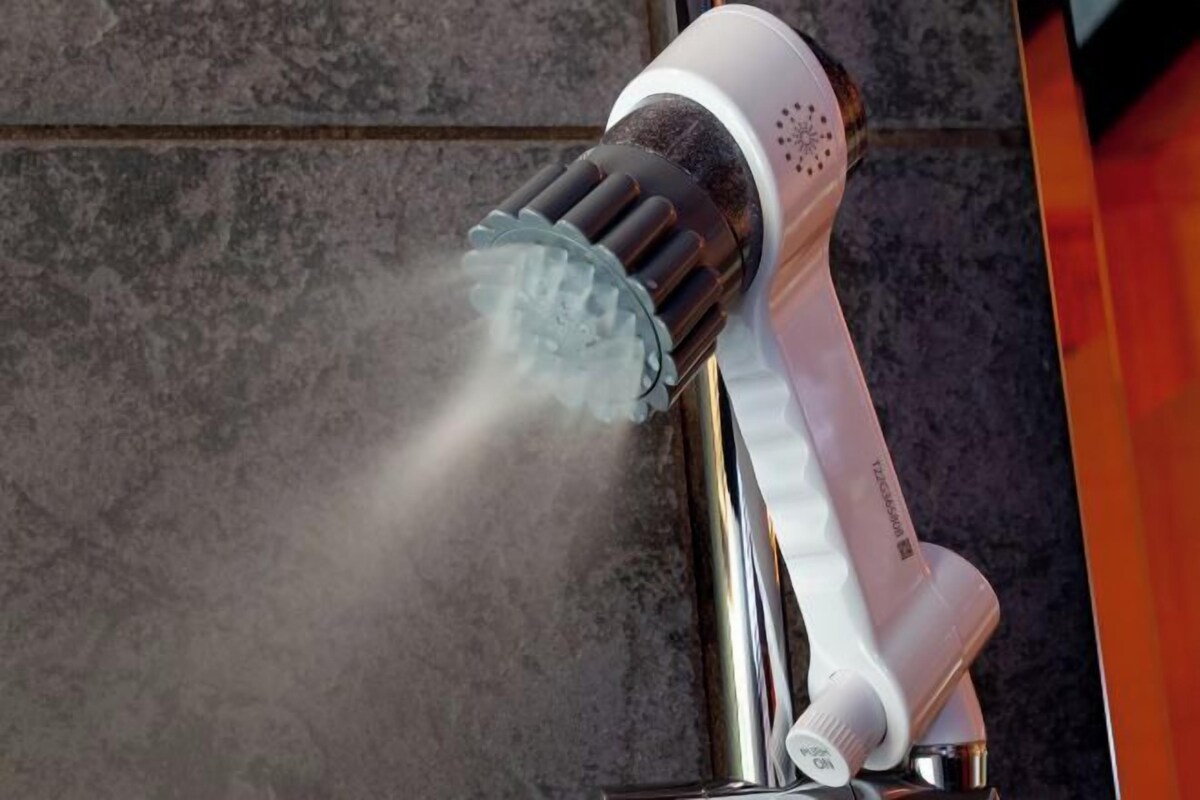 A handheld showerhead with water spray, mounted on a wall.