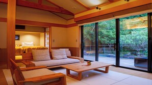 Una habitación moderna con sofá, una mesa de centro de madera y una cama con vistas a través de amplios ventanales.
