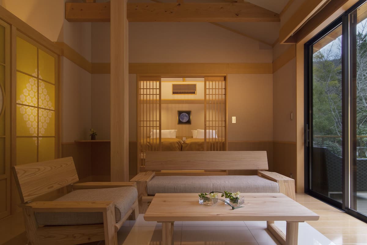Una habitación tradicional japonesa con suelo de tatami, una mesa de madera baja y un puertas correderas que dan a otra habitación.