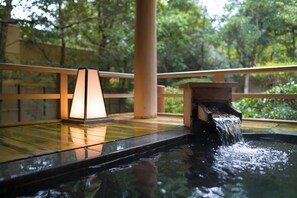 A hot spring area with a wooden deck, a water feature, and a lamp.
