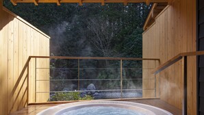 Un jacuzzi en una terraza de madera con vista a un bosque.