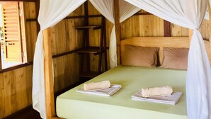 A wooden room with a bed under a white canopy. - BaraCoco Bungalows (Bira)