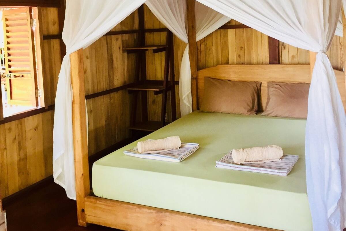 Una habitación de madera con una cama bajo un dosel blanco.