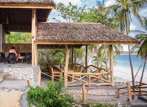 Una estructura de madera con techo de paja, rodeada de palmeras y vistas a la playa.