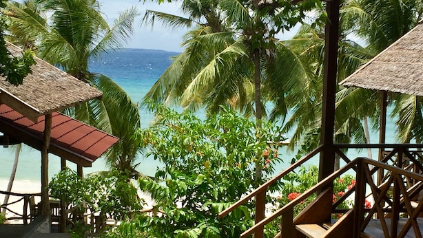 A tropical resort with a wooden staircase leading to a thatched-roof structure, overlooking a beach with palm trees and clear blue water. - BaraCoco Bungalows (Bira)